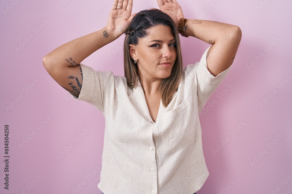 Blonde woman standing over pink background doing bunny ears gesture with hands palms looking cynical and skeptical. easter rabbit concept. Blonde woman standing over pink background doing bunny ears gesture with hands palms looking cynical and skeptical. easter rabbit concept.