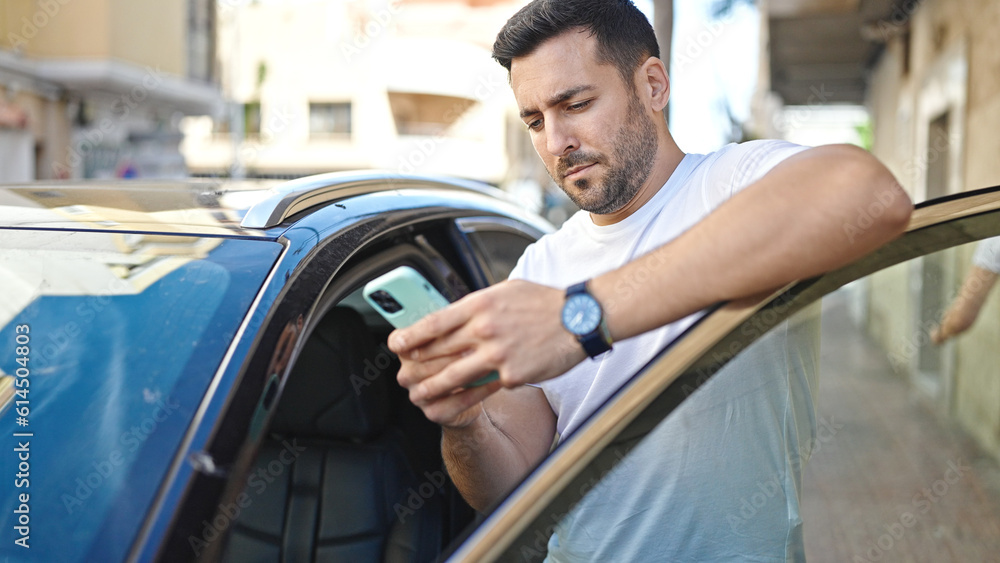 Young hispanic man using smartphone leaning on car at street Young hispanic man using smartphone leaning on car at street