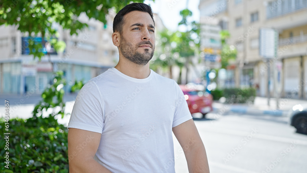 Young hispanic man looking to the side with serious expression at street