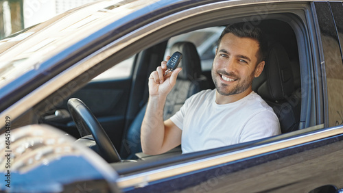 Young hispanic man smiling confident holding key of new car at street © Krakenimages.com