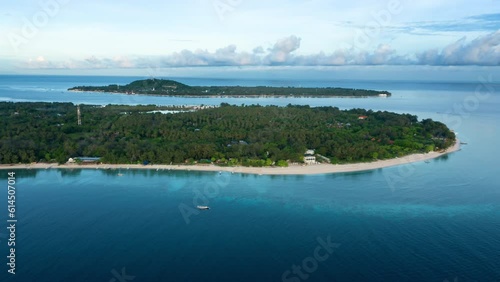 Approach to green tropical island gili meno in ocean. Aerial footage of sandy shore with vegetation in summer. Drone filming turquoise water and land with touristic resorts and sea reef for diving. photo