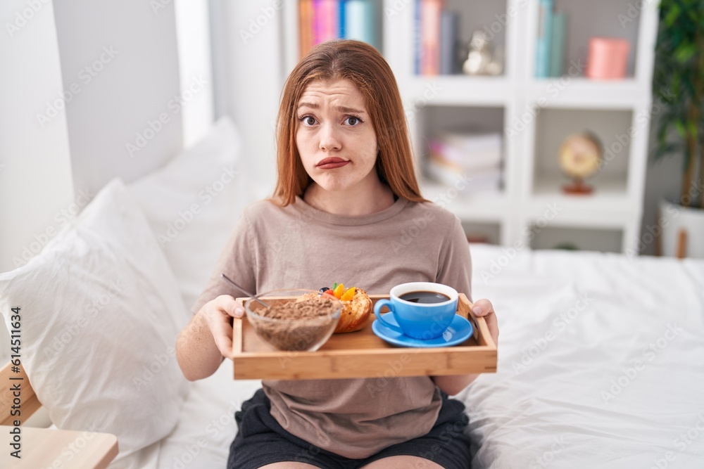 Redhead woman wearing pajama holding breakfast tray skeptic and nervous, frowning upset because of problem. negative person.