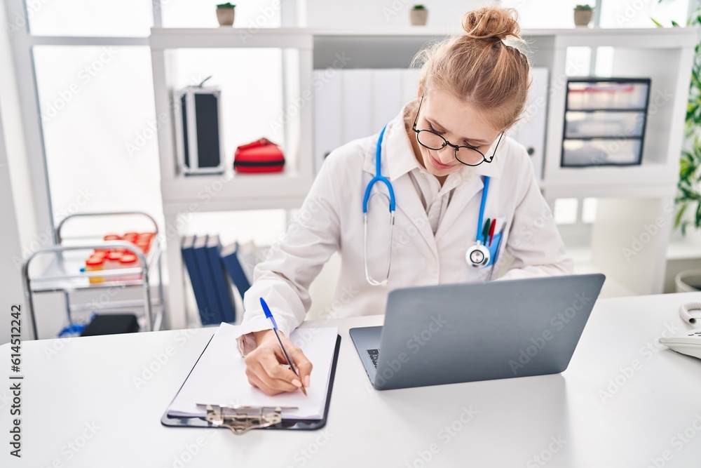 Young blonde woman doctor using laptop writing medical report at clinic Young blonde woman doctor using laptop writing medical report at clinic