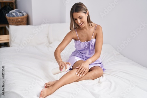 Young beautiful hispanic woman applying skin cream treatment sitting on bed at bedroom © Krakenimages.com
