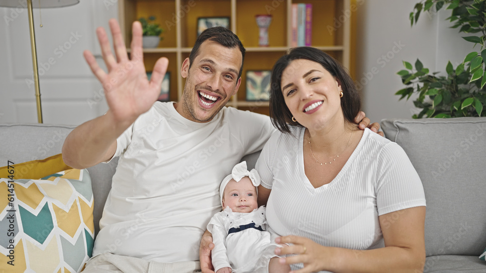 Family of three waving sitting on the sofa at home Family of three waving sitting on the sofa at home