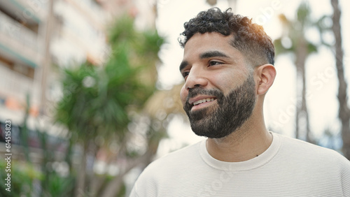 Young hispanic man smiling confident looking to the side at park