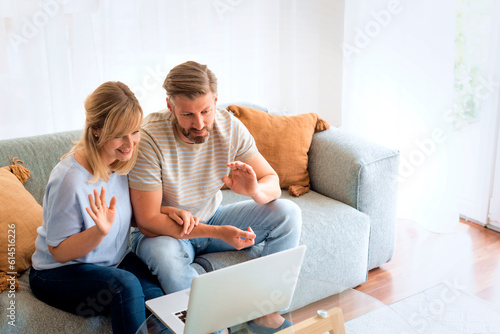 Woman and man sitting at home on the sofa and using laptop for video call