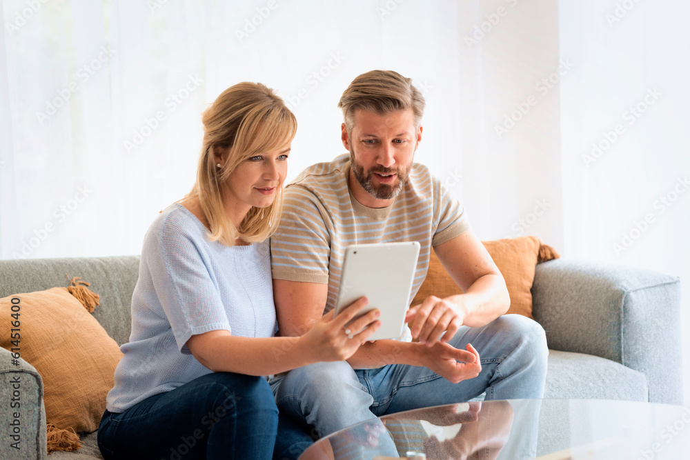 Woman and man sitting at home on the sofa and using touchpad Woman and man sitting at home on the sofa and using touchpad