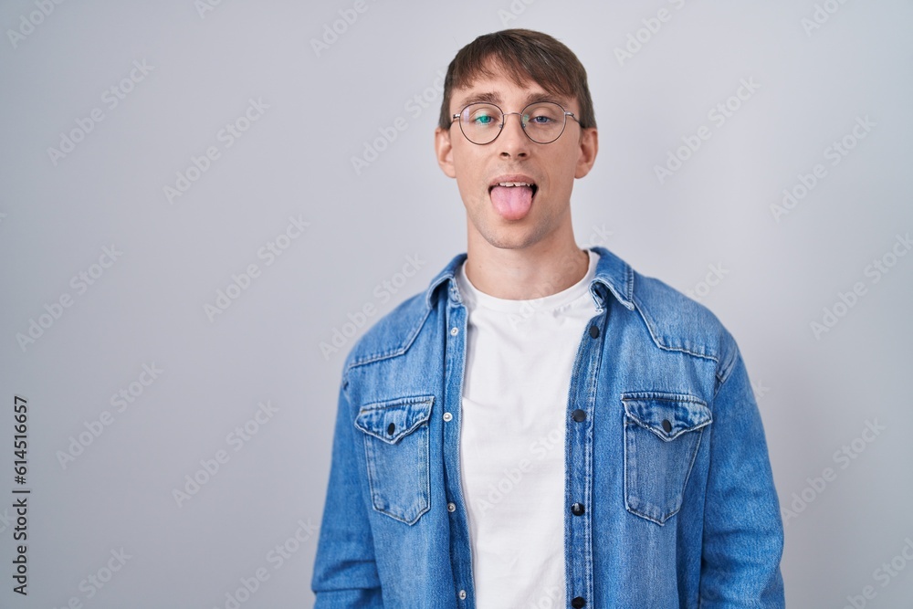 Fototapeta premium Caucasian blond man standing wearing glasses sticking tongue out happy with funny expression. emotion concept.