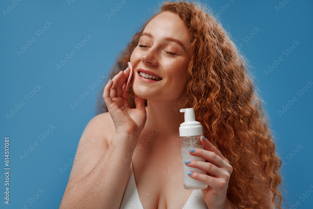 Redhead girl with freckles on a blue background Redhead girl with freckles on a blue background