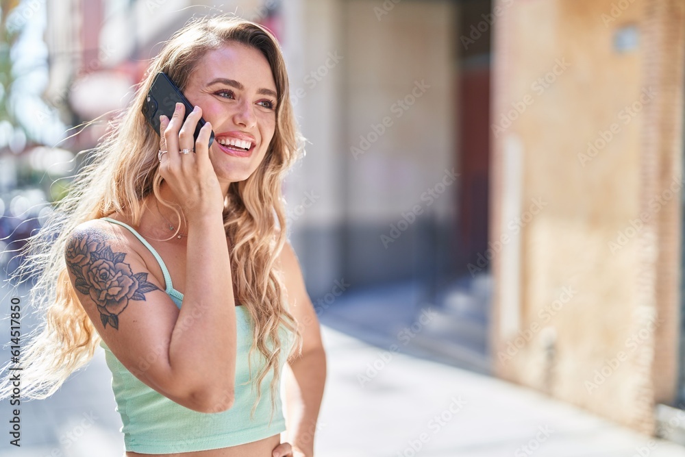 Fototapeta premium Young blonde woman smiling confident talking on the smartphone at street