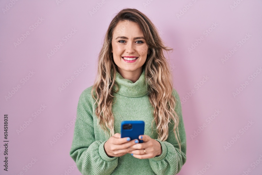 Young caucasian woman using smartphone typing message smiling with a happy and cool smile on face. showing teeth. Young caucasian woman using smartphone typing message smiling with a happy and cool smile on face. showing teeth.