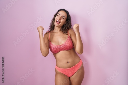 Young hispanic woman wearing lingerie over pink background celebrating surprised and amazed for success with arms raised and eyes closed. winner concept.