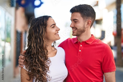 Young hispanic couple smiling confident hugging each other at street