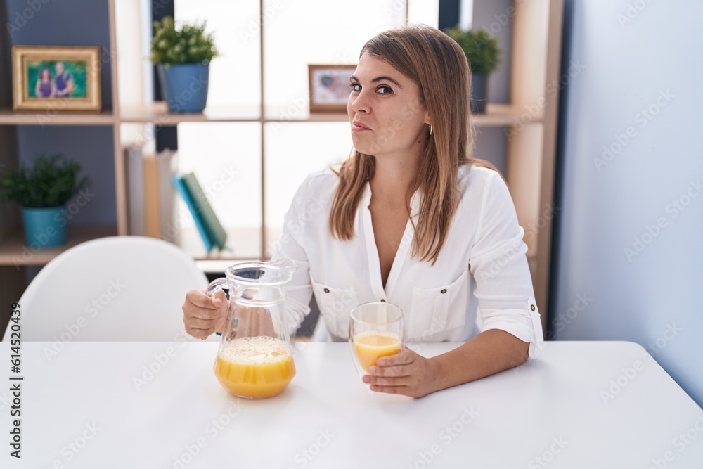 Young hispanic woman drinking glass of orange juice smiling looking to the side and staring away thinking. Young hispanic woman drinking glass of orange juice smiling looking to the side and staring away thinking.