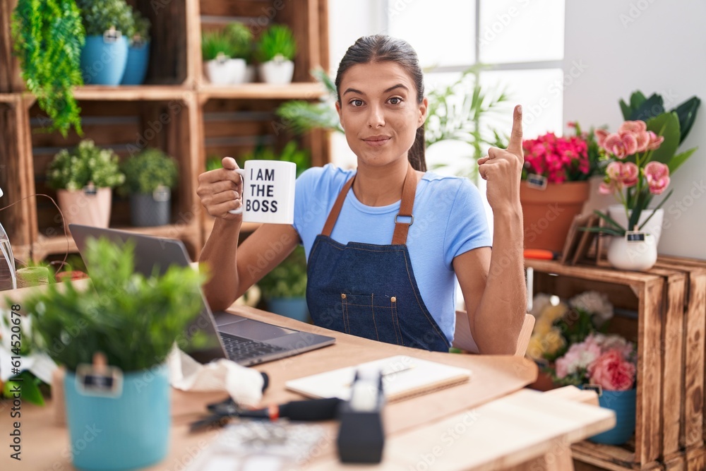 Brunette young woman working at florist shop holding i am the boss cup smiling with an idea or question pointing finger with happy face, number one Brunette young woman working at florist shop holding i am the boss cup smiling with an idea or question pointing finger with happy face, number one