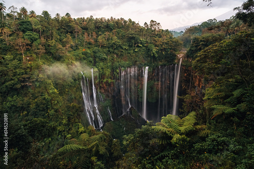 View from above  stunning aerial view of the Tumpak Sewu Waterfalls also known as Coban Sewu with the Semeru volcano in the distance  Malang Regency East Java  Indonesia.