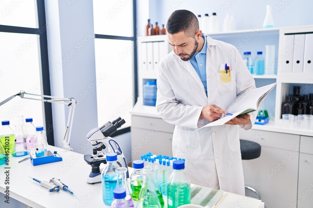 Young latin man scientist writing on notebook at laboratory Young latin man scientist writing on notebook at laboratory