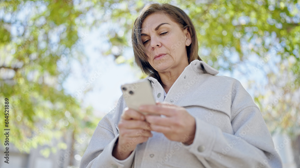 Middle age hispanic woman using smartphone at park Middle age hispanic woman using smartphone at park
