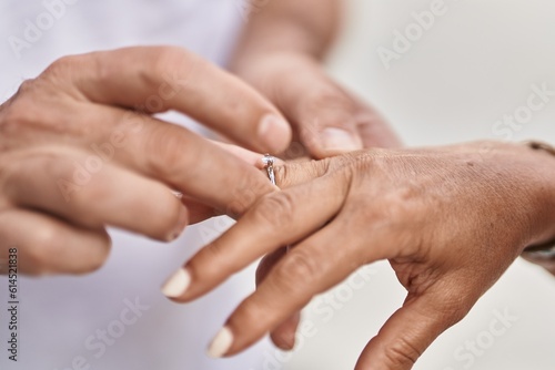 Man and woman couple putting engagement ring at street