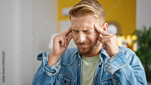 Young caucasian man suffering for headache at home