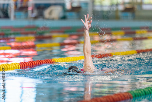Professional female athlete swimming backstroke in the pool  arms movement. Competitive swimming drills concept.