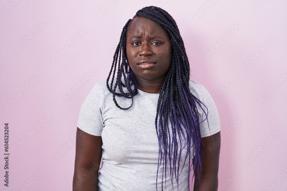 Fototapeta premium Young african woman standing over pink background looking sleepy and tired, exhausted for fatigue and hangover, lazy eyes in the morning.