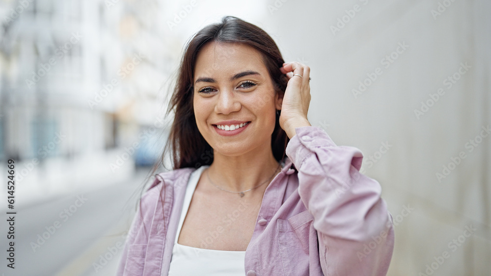Young beautiful hispanic woman smiling confident combing hair with hand at street