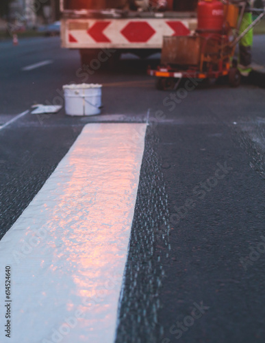 Process of making new road surface markings with a line striping machine  workers improve city infrastructure  demarcation marking of pedestrian crossing with hot melted paint on asphalt pavement