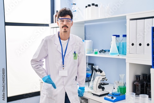 Young caucasian man scientist standing with relaxed expression at laboratory