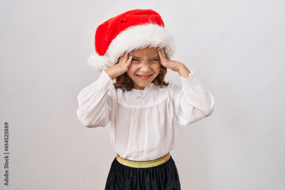 Little hispanic girl wearing christmas hat with hand on head, headache because stress. suffering migraine. Little hispanic girl wearing christmas hat with hand on head, headache because stress. suffering migraine.