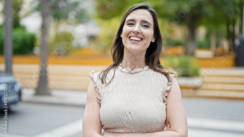 Young beautiful hispanic woman standing with crossed arms at street