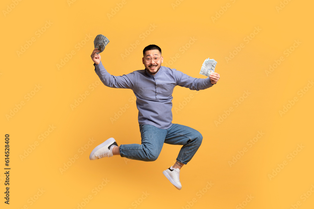 Big Win. Asian Guy Jumping In Air With Dollar Cash In Hands