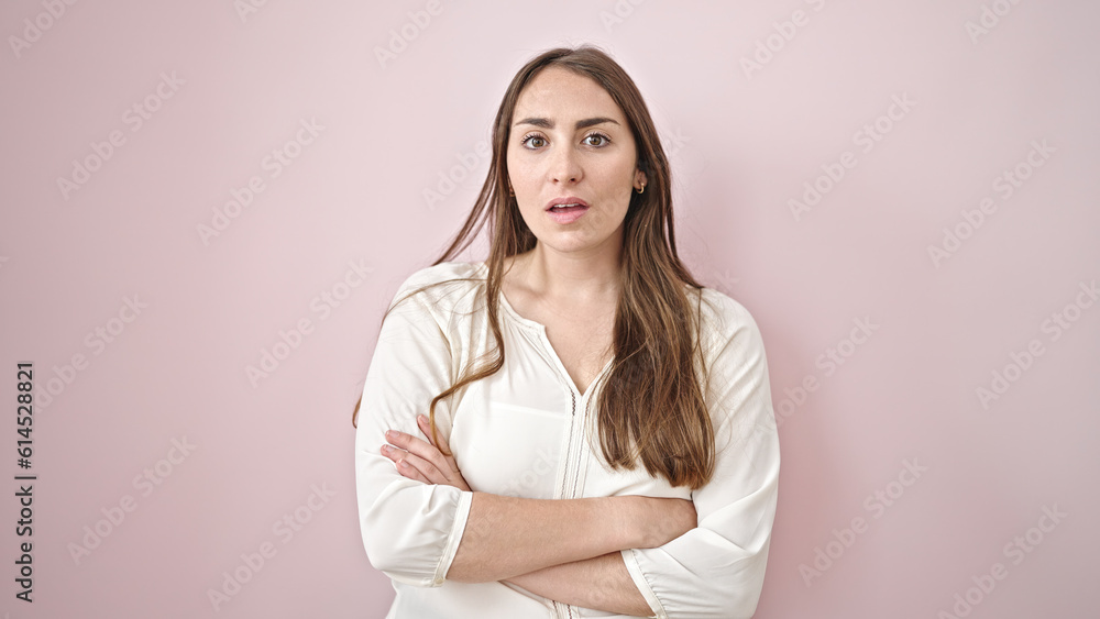 Fototapeta premium Young beautiful hispanic woman standing with serious expression and arms crossed gesture over isolated pink background
