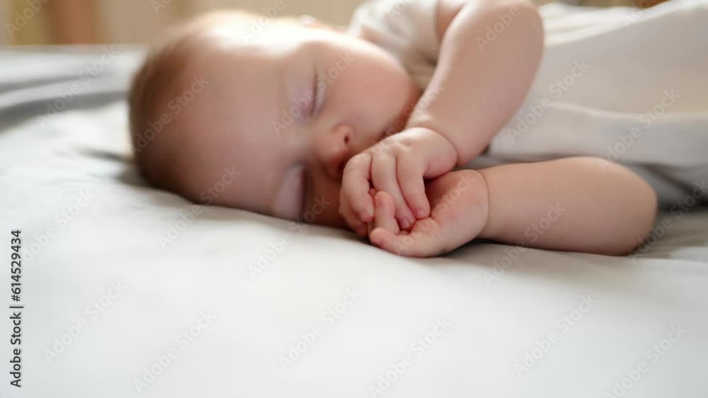 Cute baby sleeps peacefully in his crib at home, lying on his side.The concept of independent sleep,childhood protection Cute baby sleeps peacefully in his crib at home, lying on his side.The concept of independent sleep,childhood protection