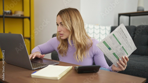 Young beautiful hispanic woman using laptop doing accounting at home