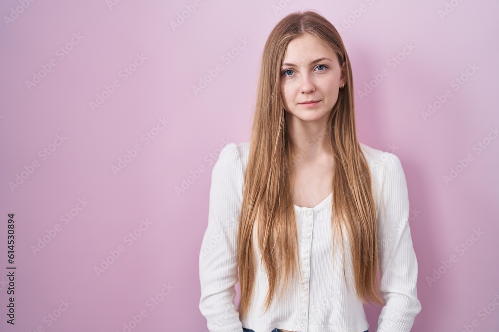 Young caucasian woman standing over pink background relaxed with serious expression on face. simple and natural looking at the camera. Young caucasian woman standing over pink background relaxed with serious expression on face. simple and natural looking at the camera.