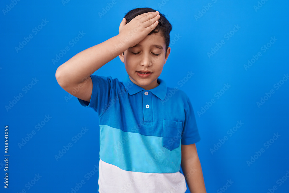 Little hispanic boy standing over blue background surprised with hand on head for mistake, remember error. forgot, bad memory concept. Little hispanic boy standing over blue background surprised with hand on head for mistake, remember error. forgot, bad memory concept.