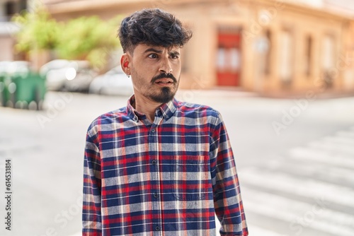 Young hispanic man standing with fear expression at street