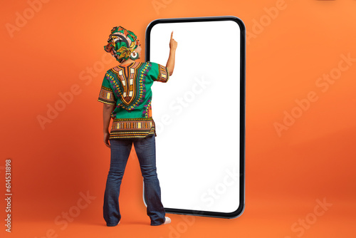 Black woman in african costume touching blank phone screen © Prostock-studio