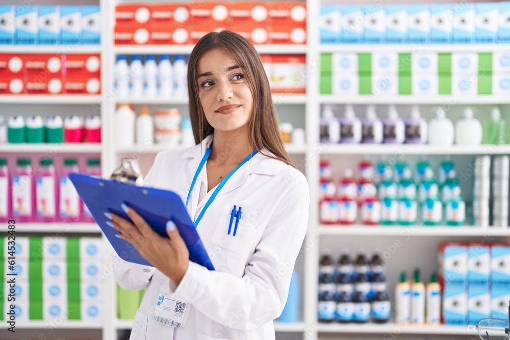 Young beautiful hispanic woman pharmacist smiling confident writing on document at pharmacy Young beautiful hispanic woman pharmacist smiling confident writing on document at pharmacy