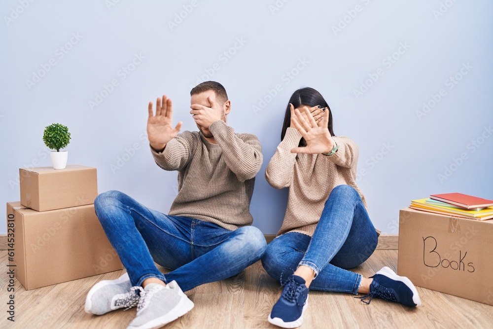 Young couple moving to a new home covering eyes with hands and doing stop gesture with sad and fear expression. embarrassed and negative concept. Young couple moving to a new home covering eyes with hands and doing stop gesture with sad and fear expression. embarrassed and negative concept.