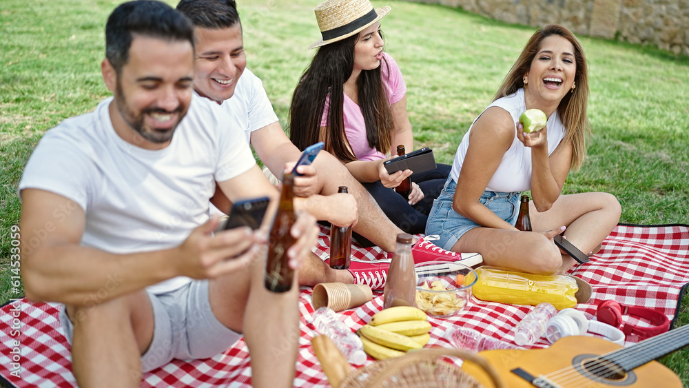 Group of people having picnic using smartphones and touchpad at park Group of people having picnic using smartphones and touchpad at park