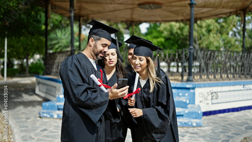Group of people students graduated holding diploma looking smartphone screen at university campus