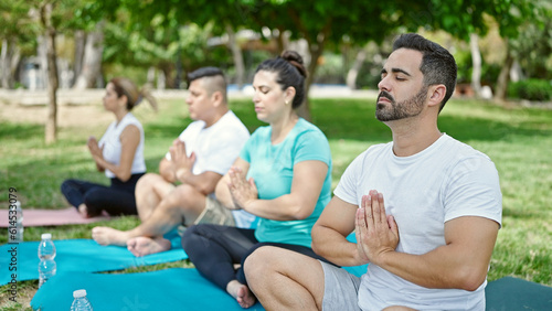 Group of people training yoga sitting on mat at park