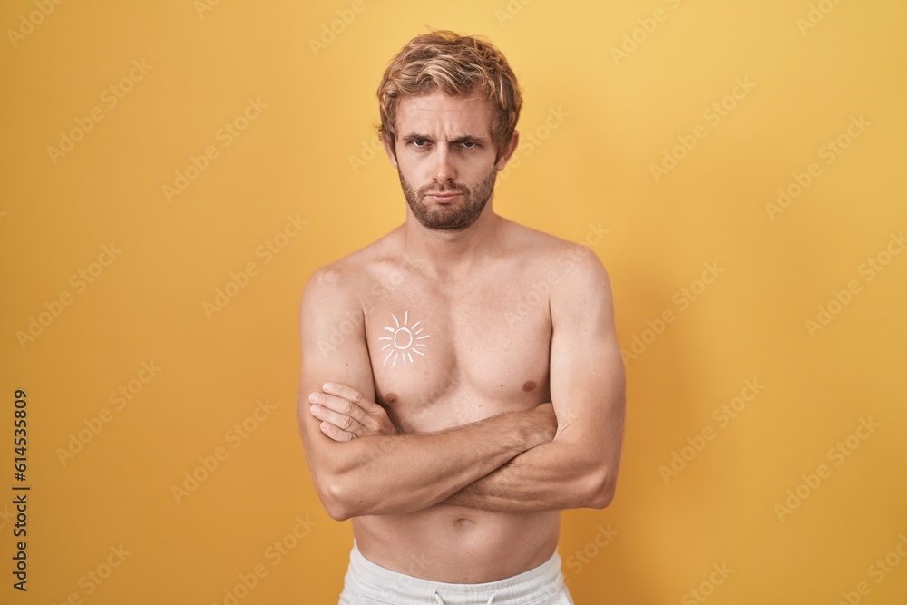 Caucasian man standing shirtless wearing sun screen skeptic and nervous, disapproving expression on face with crossed arms. negative person.
