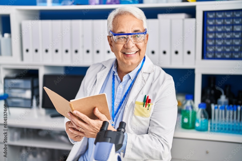 Senior man scientist reading book at laboratory Senior man scientist reading book at laboratory