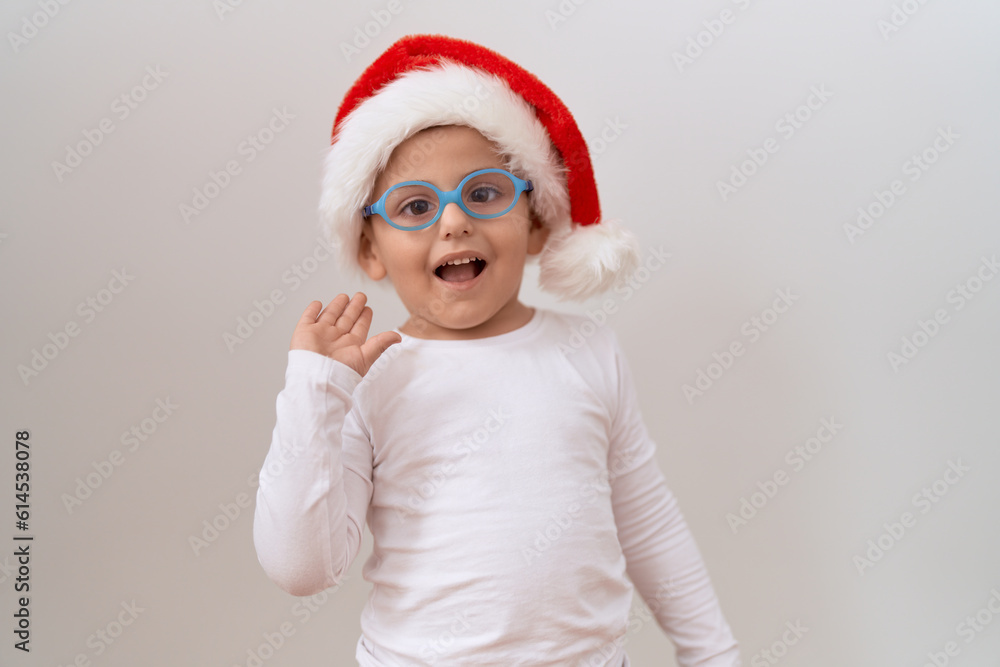 Little hispanic boy wearing glasses and christmas hat celebrating achievement with happy smile and winner expression with raised hand