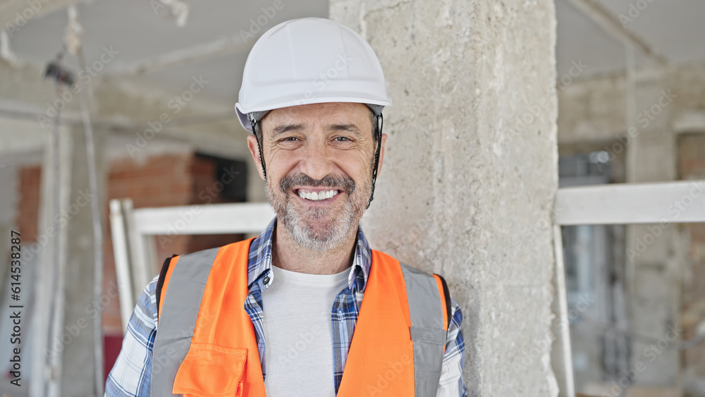 Middle age man builder smiling confident standing at construction site