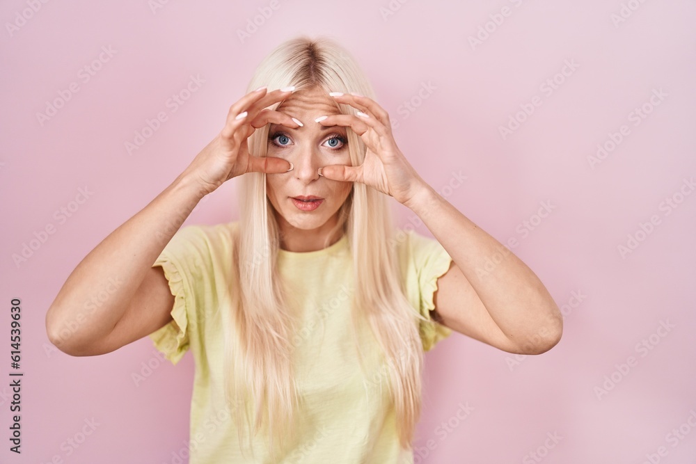 Caucasian woman standing over pink background trying to open eyes with fingers, sleepy and tired for morning fatigue Caucasian woman standing over pink background trying to open eyes with fingers, sleepy and tired for morning fatigue